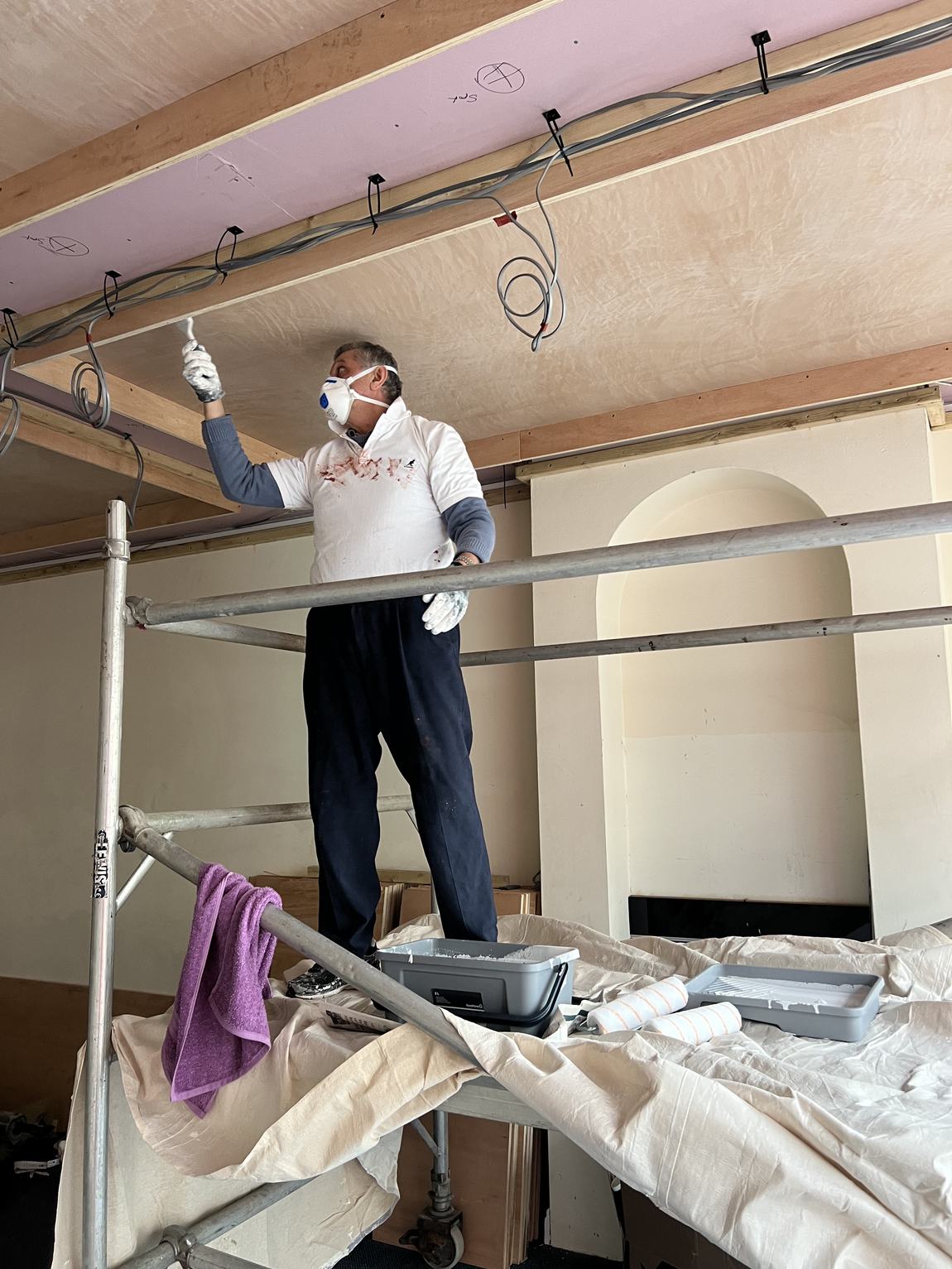Behrouz painting the ceiling from the scaffold