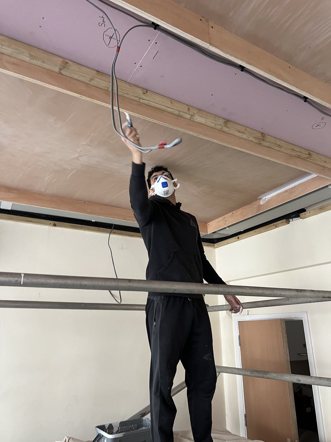 Pulling cable through the ceiling from a scaffold tower