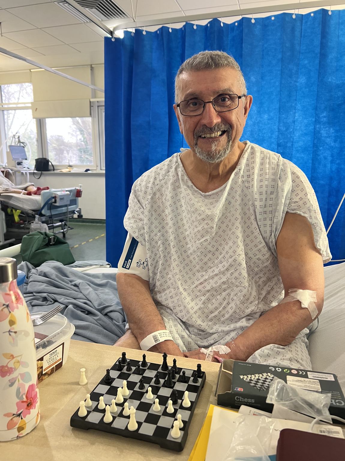 Behrouz in hospital, smiling, with a chessboard
